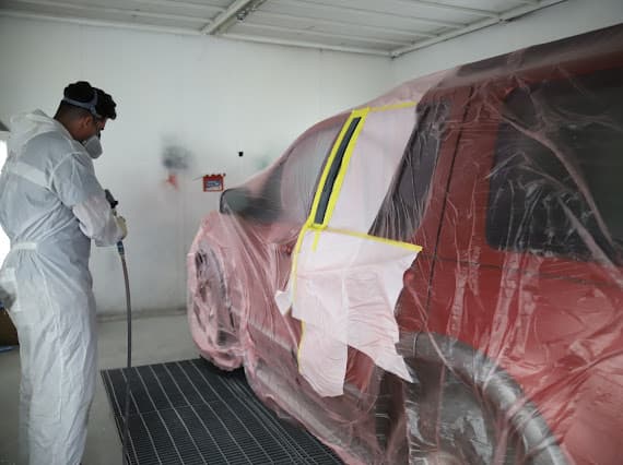 Auto paint refinishing technician spraying vehicle at Best Class Auto Body Las Vegas